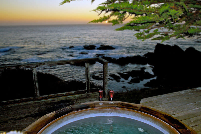 view from the hot tub looking out at the ocean with two wine glasses
